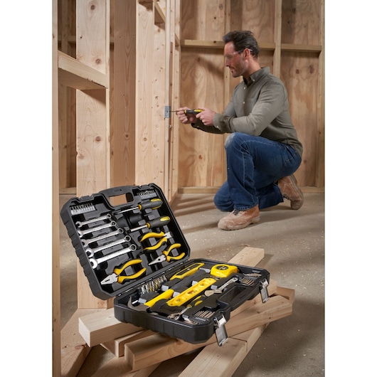 STANLEY STHT78050-1 tool kit case with assorted hand tools, shown open on wooden planks at a construction site.