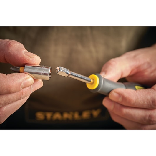 STANLEY STMT13910-0 hand holding ratchet screwdriver and detachable socket with bit, close-up photo.