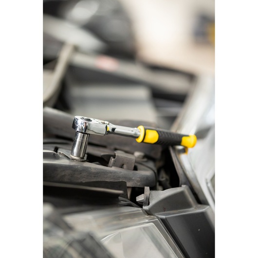 STANLEY STMT82663-0 ratchet wrench with yellow and black handle used on automotive part, side view.
