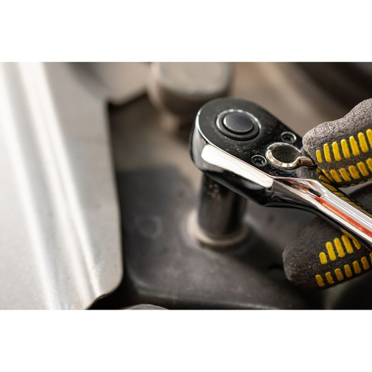 STANLEY STMT82663-0 ratchet tool in use, close-up view, held by gloved hand on mechanical part.