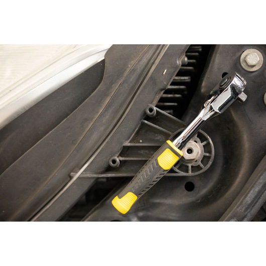 STANLEY STMT82663-0 ratchet with yellow and black handle used on engine part, close-up photography.