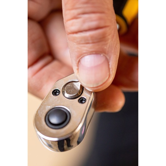 Close-up of hand using STANLEY STMT82663-0 ratchet wrench head, showing thumb pressing direction switch.