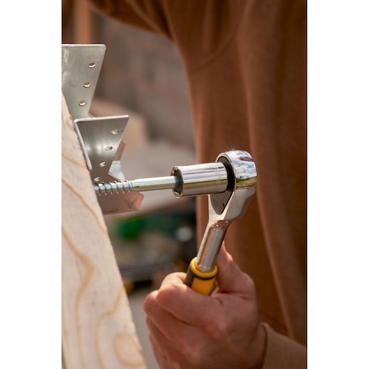 STANLEY STMT82665-0 ratchet tool in use, close-up side view, silver and yellow handle, fastening a screw.