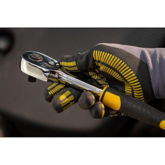 STANLEY STMT82665-0 ratchet wrench held in gloved hand, close-up, showing ergonomic handle and chrome finish.