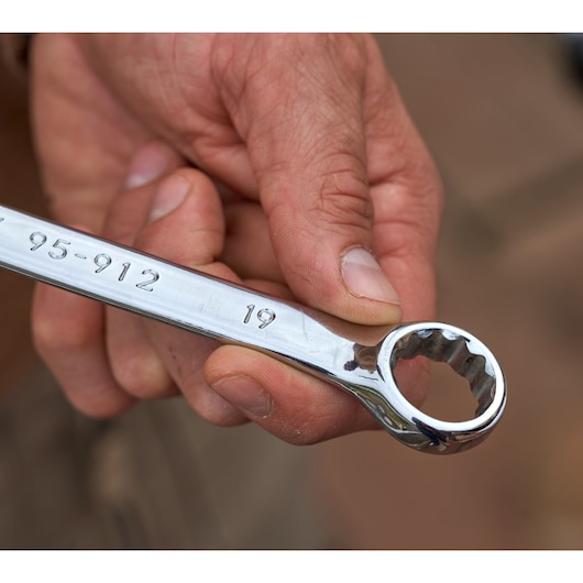 Close-up of STANLEY STMT82843-0 combination wrench from 12-piece set, held in hand, showing chrome finish.