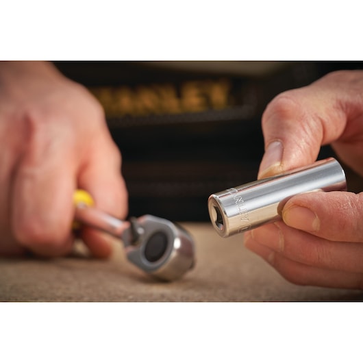 STANLEY STMT86116-0 socket held in hand, with ratchet wrench tool in background, close-up photo.
