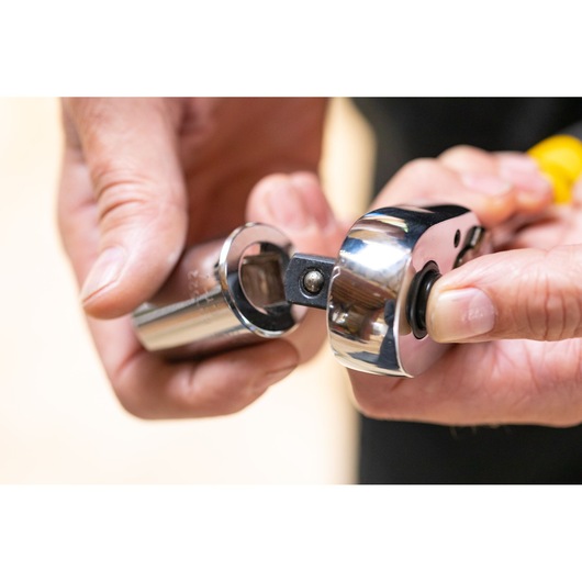 STANLEY STMT86532-0 ratchet handle with chrome socket attachment held in hand, close-up photo.