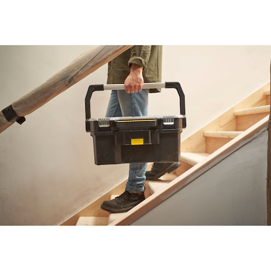STANLEY STST1-70317 black toolbox with silver handle being carried up stairs, product photography.