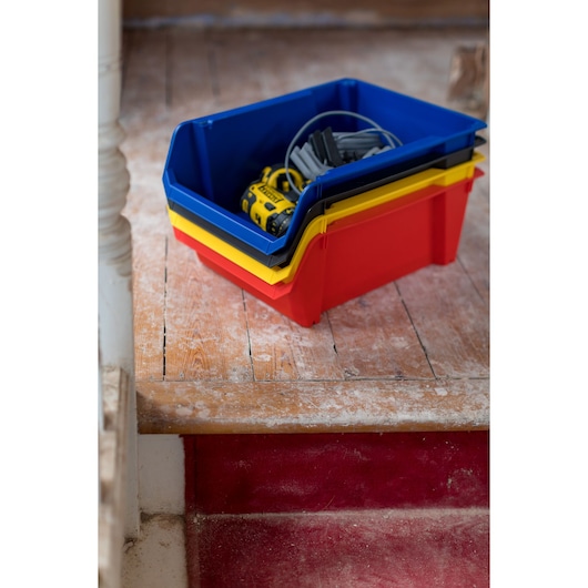 STANLEY STST82745-1 stackable storage bins in red, yellow, and blue with tools on wooden floor.