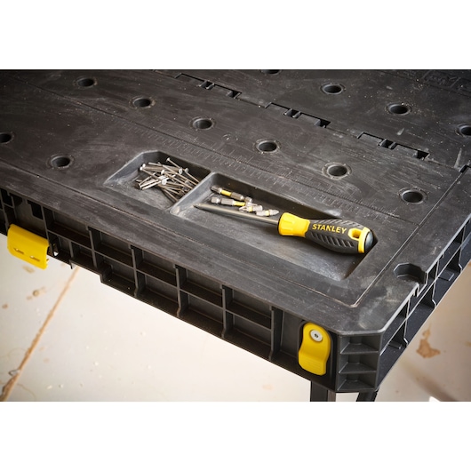 STANLEY STST83492-1 black workbench with screw bits and yellow-black screwdriver in top tray, angled view.